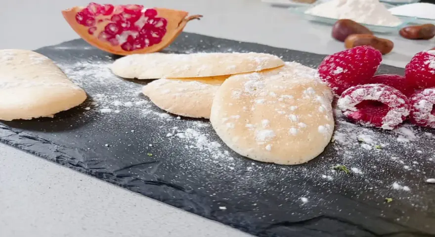 Bizcochos soletilla espolvoreados con azúcar glas, acompañados de frambuesas y granada.