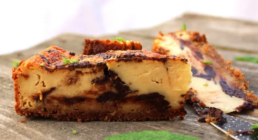 Tarta de queso con chocolate, con trozos de chocolate oscuro y una base crujiente. Perfecta para los amantes del dulce.
