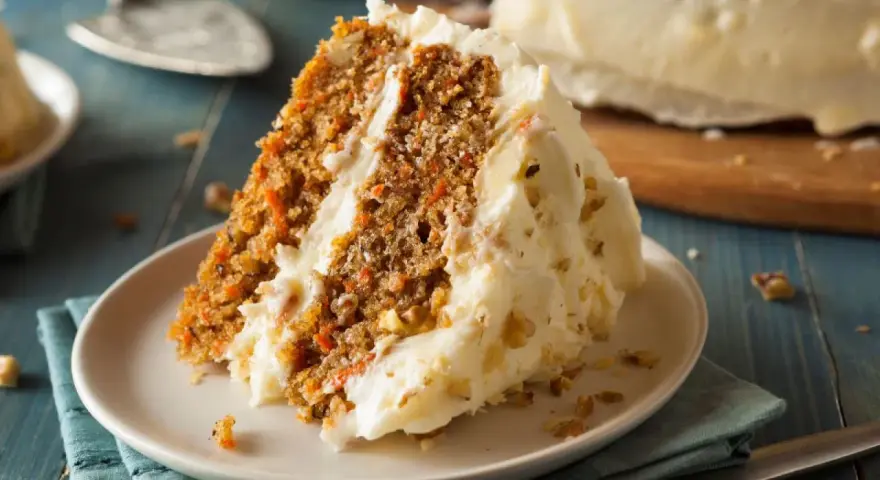Rebanada de tarta de zanahoria casera con glaseado cremoso y nueces. ¡Una delicia para tu próxima receta!
