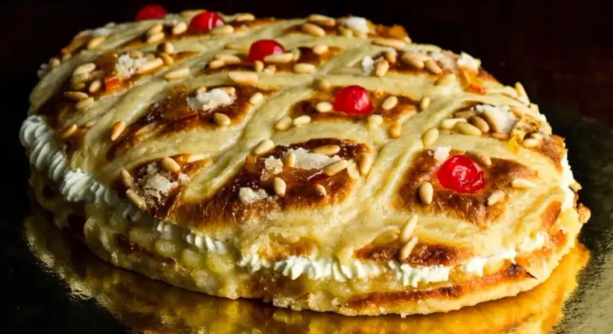 Deliciosa coca de Sant Joan rellena de crema, decorada con piñones, cerezas rojas y azúcar.