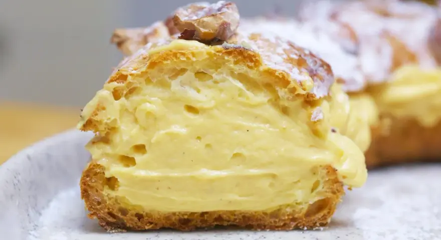 Un delicioso paris brest, un postre francés con crema pastelera y almendras, espolvoreado con azúcar glas.