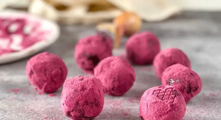 Deliciosas trufas de chocolate cubiertas de polvo rosa vibrante, algunas con un patrón grabado.