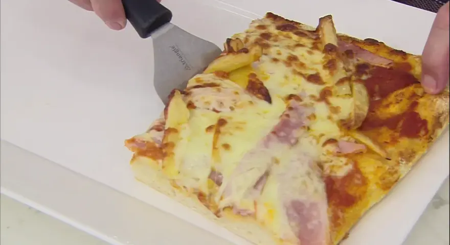 Una rebanada de pan pizza con papas fritas y jamón, lista para ser servida.
