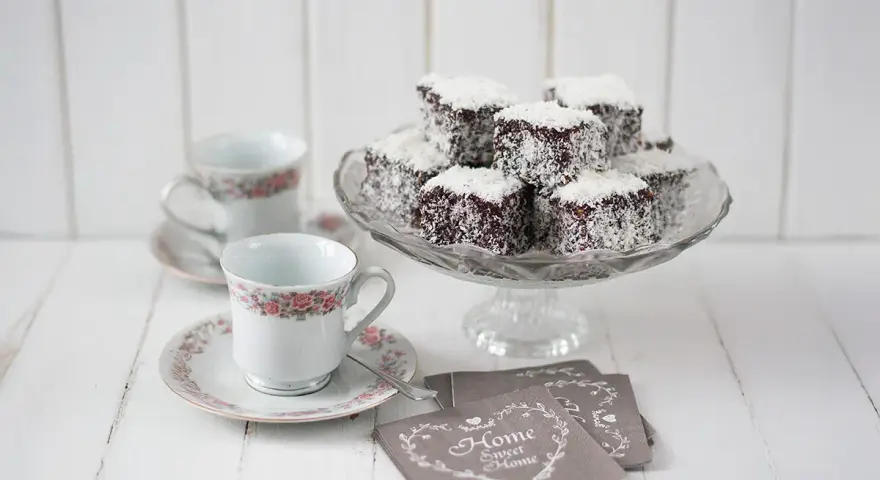 Deliciosos lamington cake cubiertos de coco, listos para disfrutar con café.