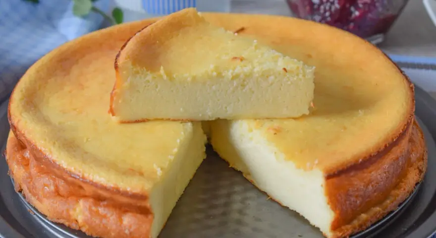 Tarta de queso y limón al horno, dorada y esponjosa, con una porción servida.