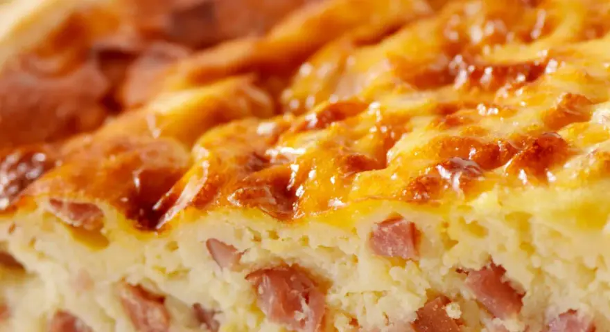 Primer plano de una deliciosa quiche Lorraine, con trozos de bacon y una dorada capa superior. ¡Perfecta para tu próxima receta!