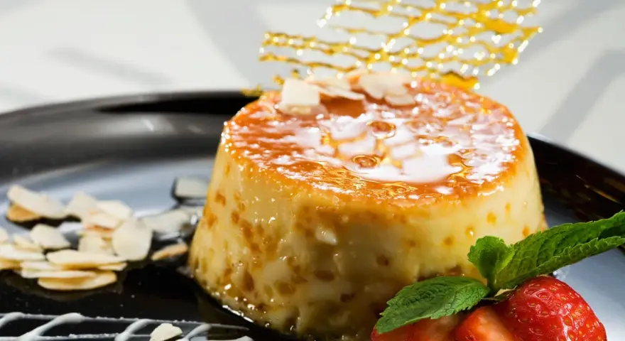 Delicioso postre de piña y leche condensada, cubierto de caramelo y decorado con almendras y fresas.
