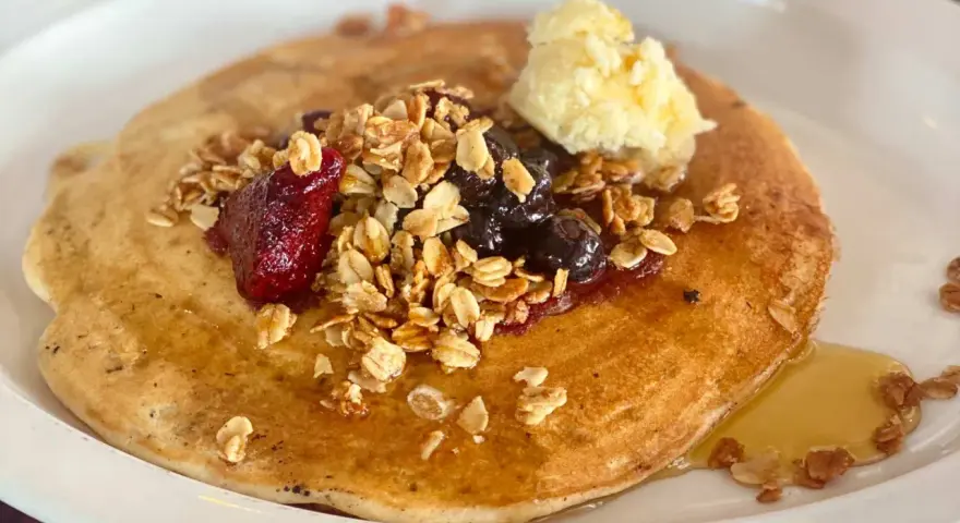 Deliciosos crepes con harina de almendras, cubiertos con granola, frutos rojos, arándanos y una porción de mantequilla.