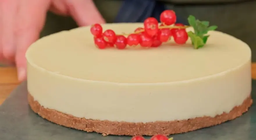 Deliciosa tarta de chocolate blanco, decorada con grosellas rojas y una hoja de menta.