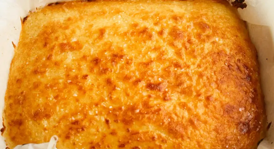 Un delicioso blondie dessert recién horneado, dorado y crujiente, listo para ser cortado y disfrutado.