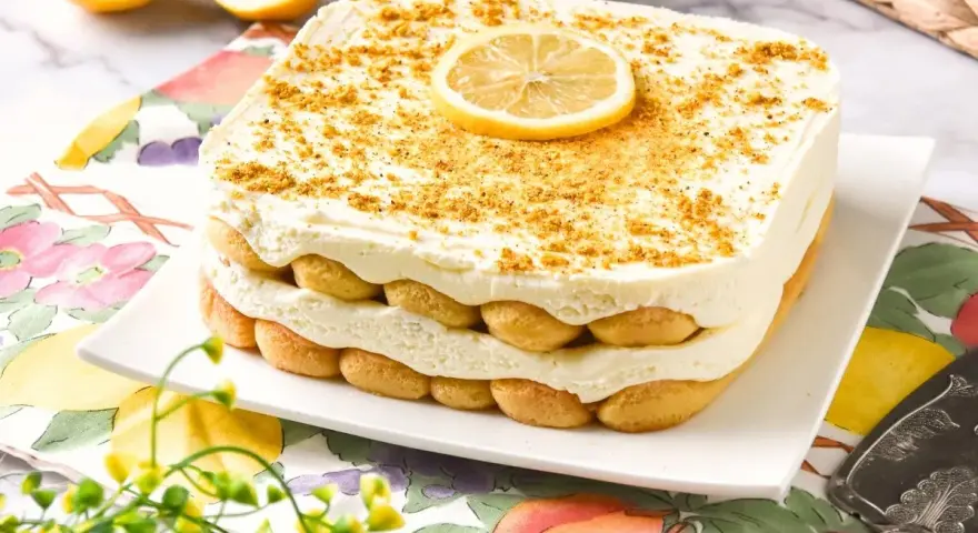 Delicioso tiramisú de limón, con capas de bizcochos y crema, coronado con una rodaja de limón y ralladura dorada.