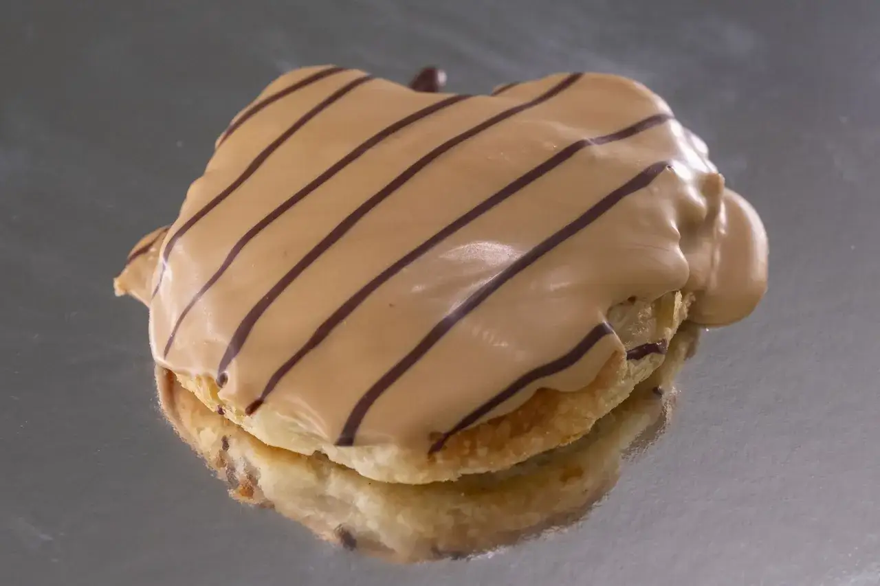 Palmeritas de hojaldre cubiertas de glaseado color caramelo y decoradas con finas l&iacute;neas de chocolate.