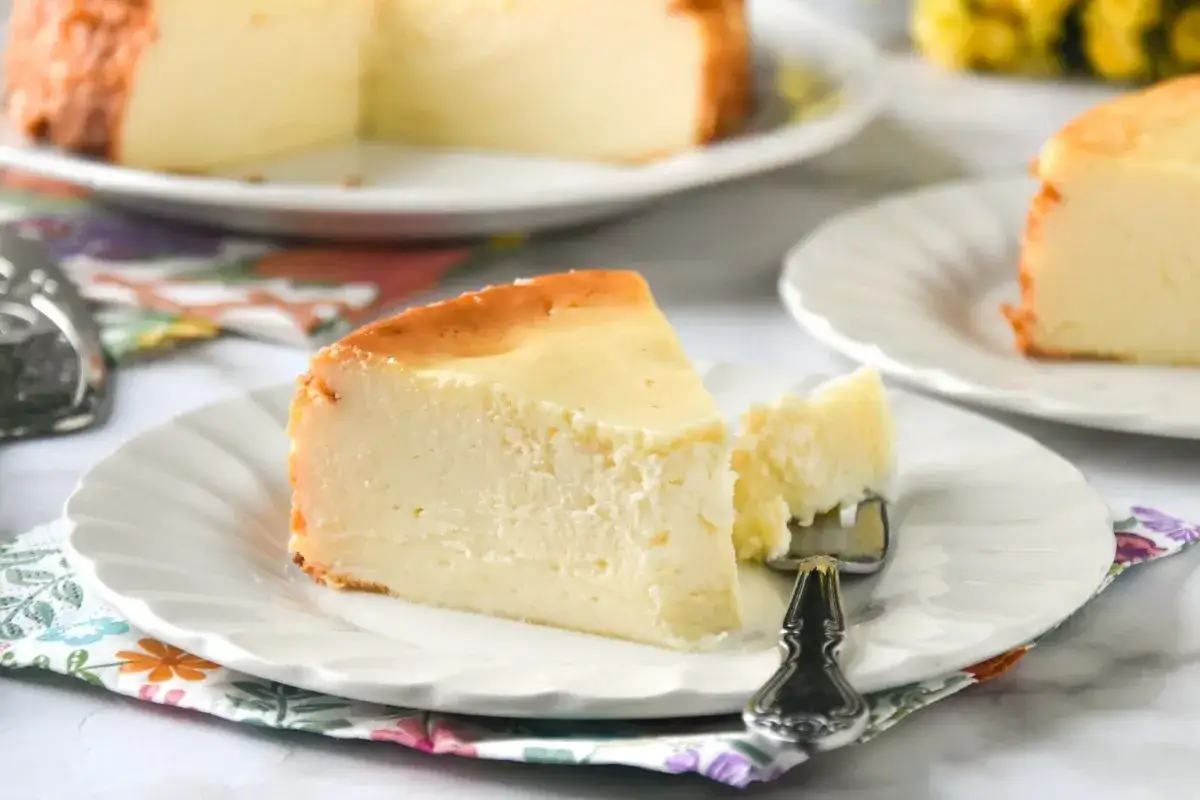 Una rebanada cremosa de tarta de reques&oacute;n, con un tenedor listo para probarla.