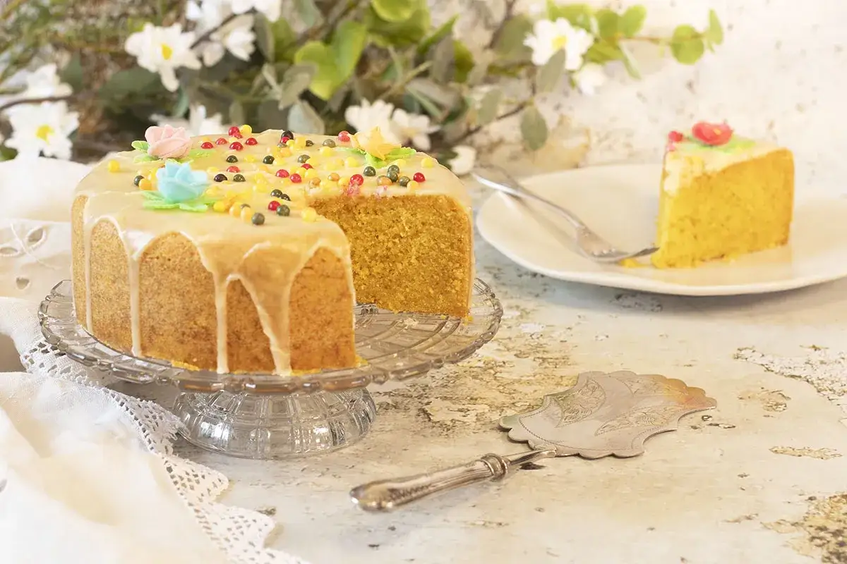 Deliciosa tarta de naranja con glaseado y decoraciones coloridas. Un trozo ya servido en un plato.