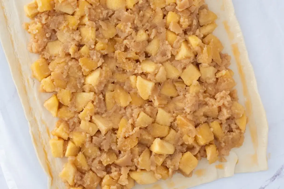 Relleno de manzana picada sobre masa de hojaldre, listo para convertirse en una deliciosa empanada de manzana.
