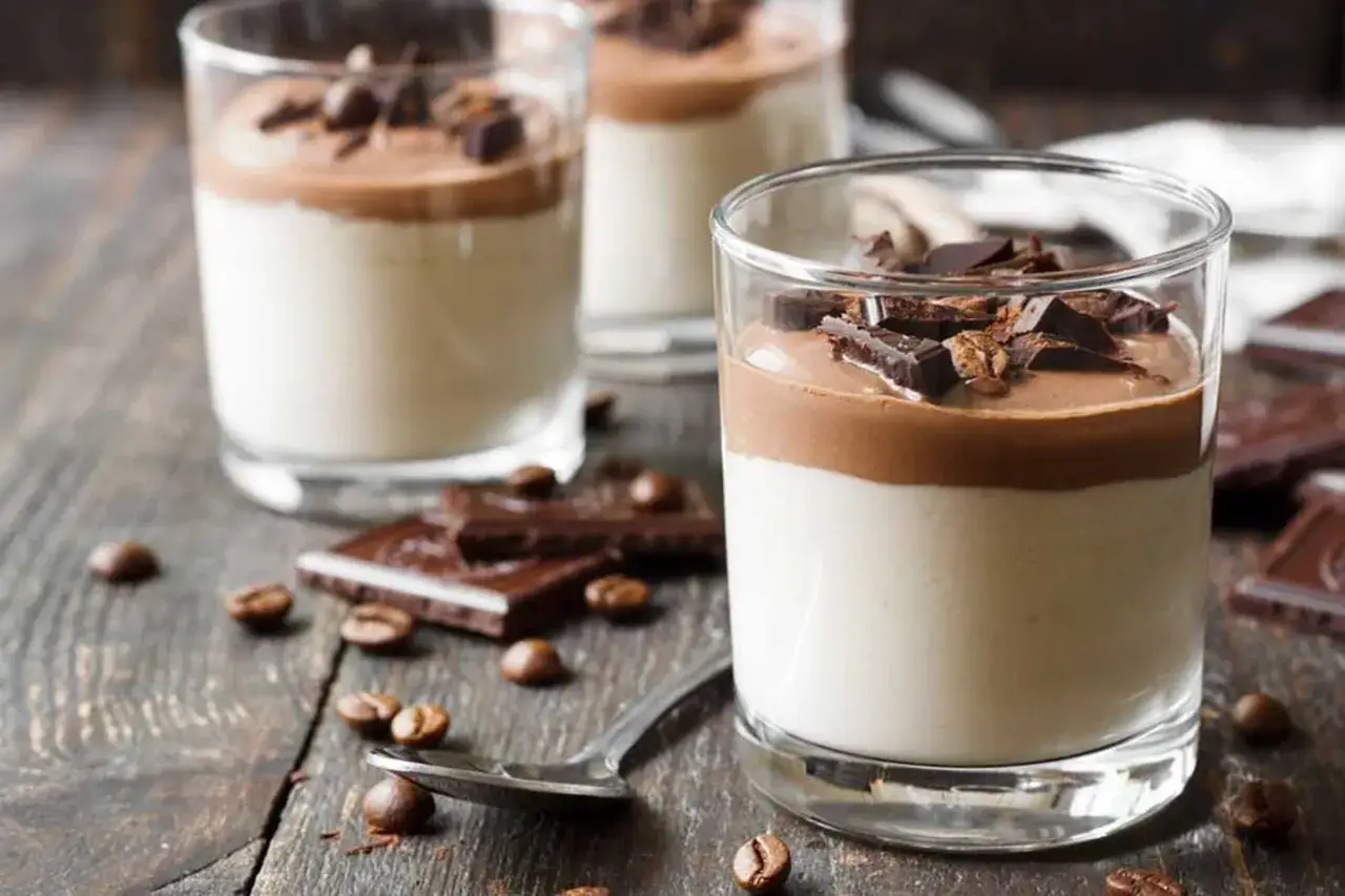 Deliciosa panna cotta de café con trozos de chocolate y granos de café esparcidos.