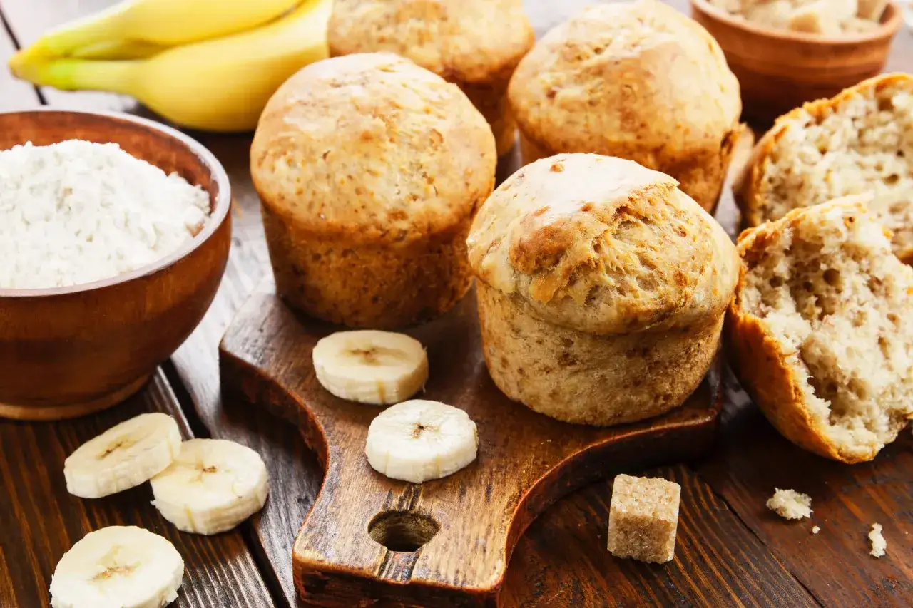 Muffins saludables de plátano, con ingredientes como harina, plátano y azúcar moreno, listos para disfrutar.