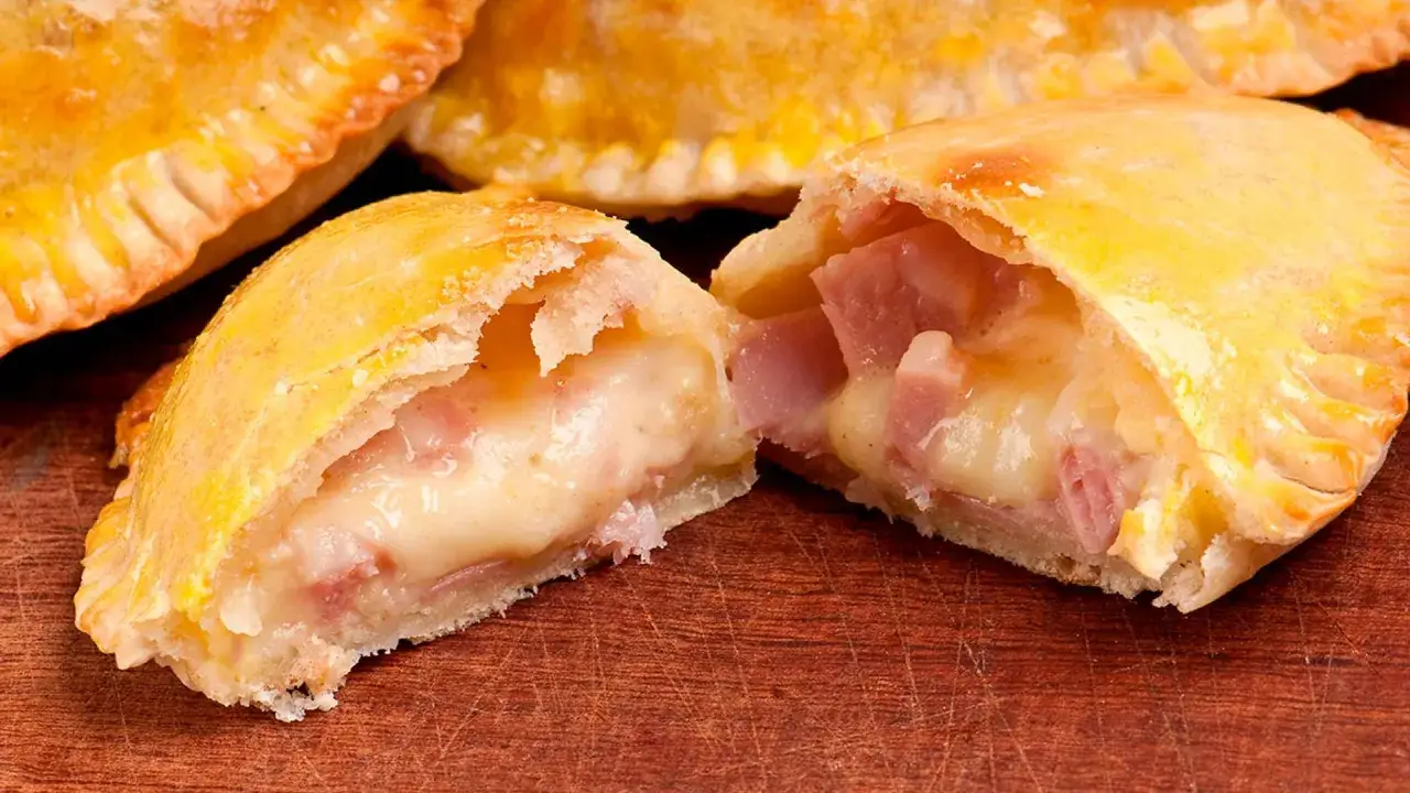 Empanadillas de jamón y queso recién horneadas, con el queso derretido y el jamón jugoso. ¡Un bocado irresistible!