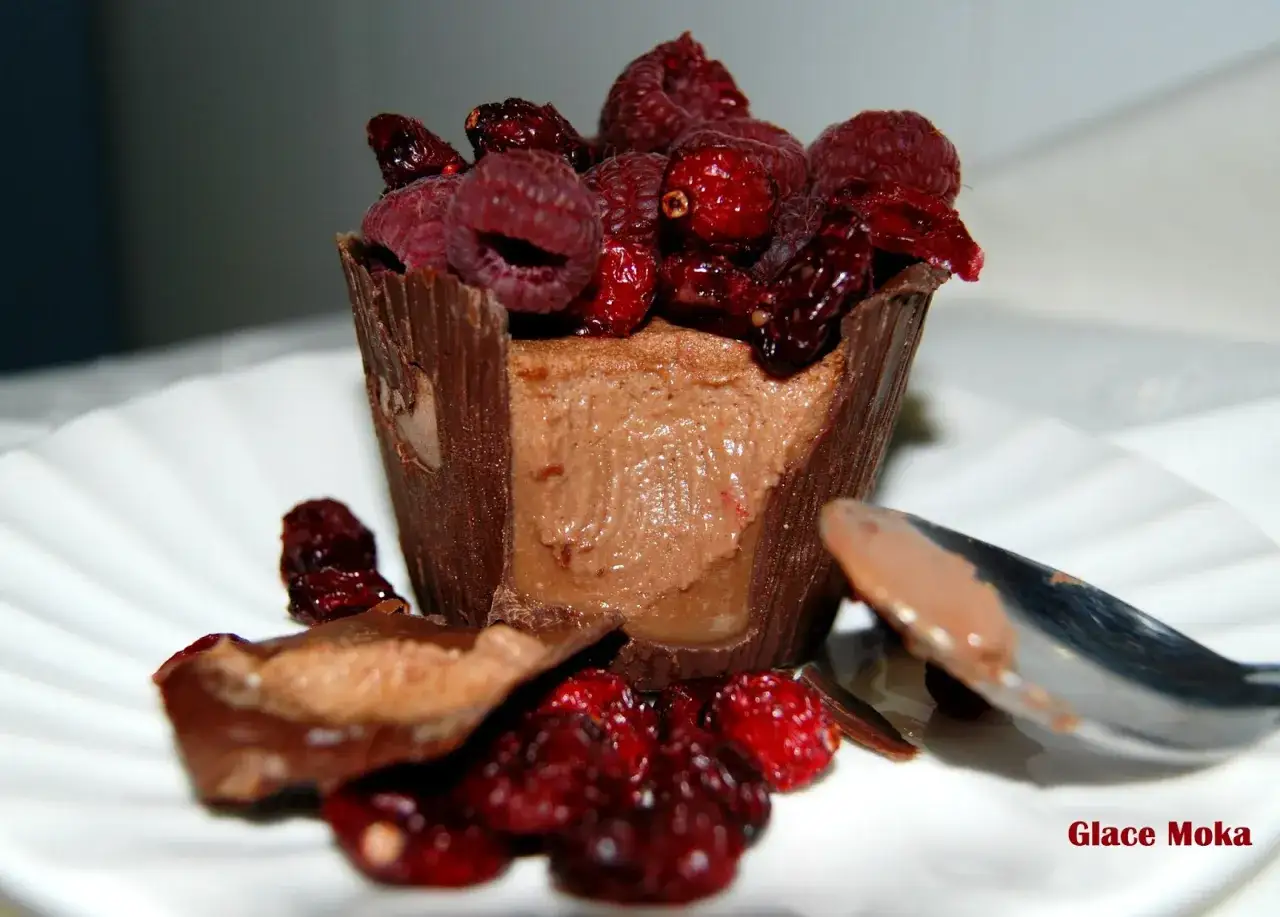 Deliciosos postres en vasitos de chocolate, coronados con frambuesas y ar&aacute;ndanos, listos para ser disfrutados.