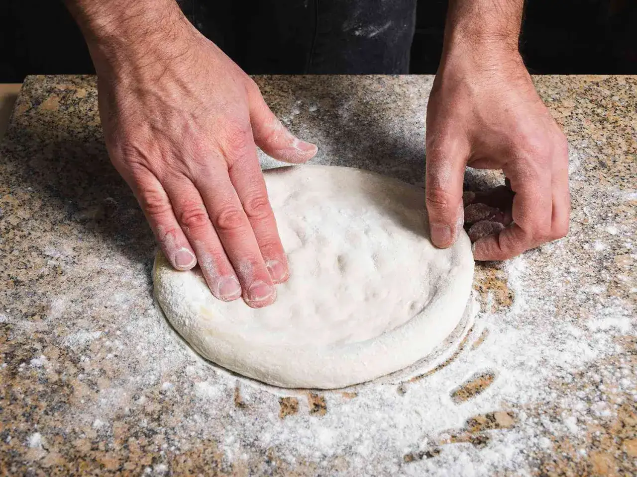 Manos formando una masa de pizza perfecta, lista para hornear. ¡La masa pizza Thermomix es fácil de hacer!