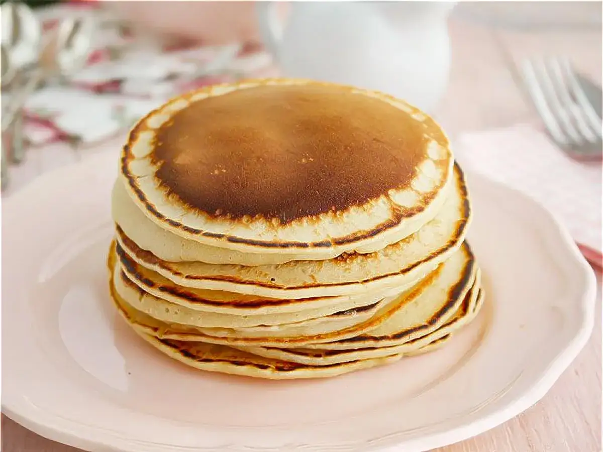 Pila de tortitas doradas y esponjosas, perfectas para aprender como hacer tortitas caseras.