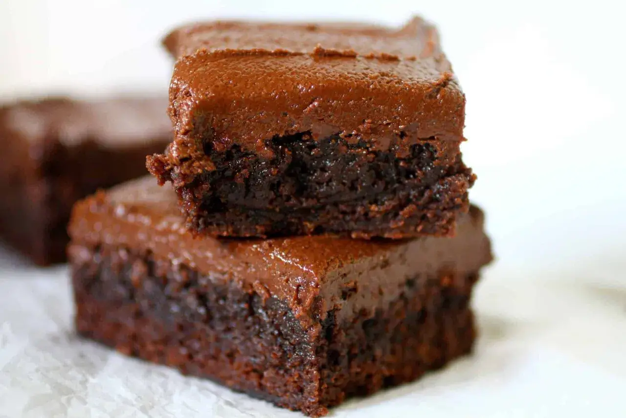 Dos deliciosos brownies de chocolate, cubiertos con glaseado cremoso, perfectos para tu receta de brownie esponjoso.