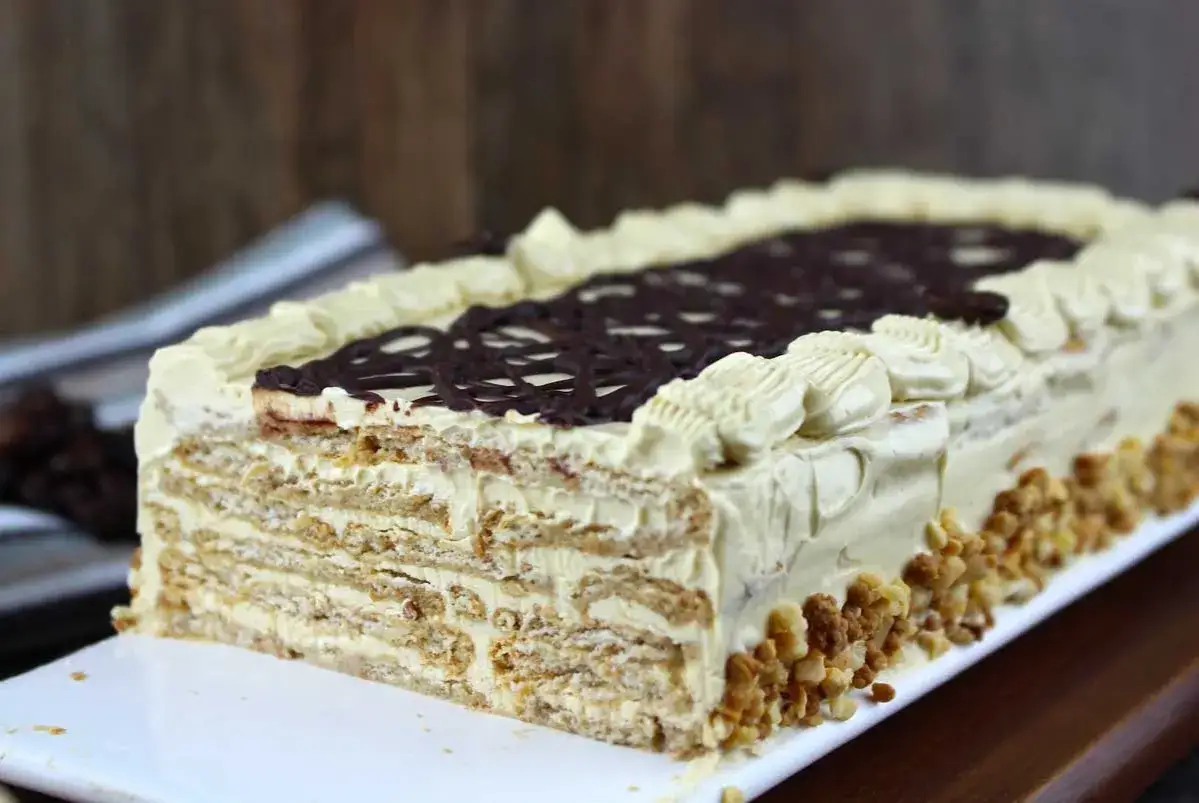 Tarta de moka rectangular, con capas de galleta y crema, cubierta de chocolate y frutos secos.