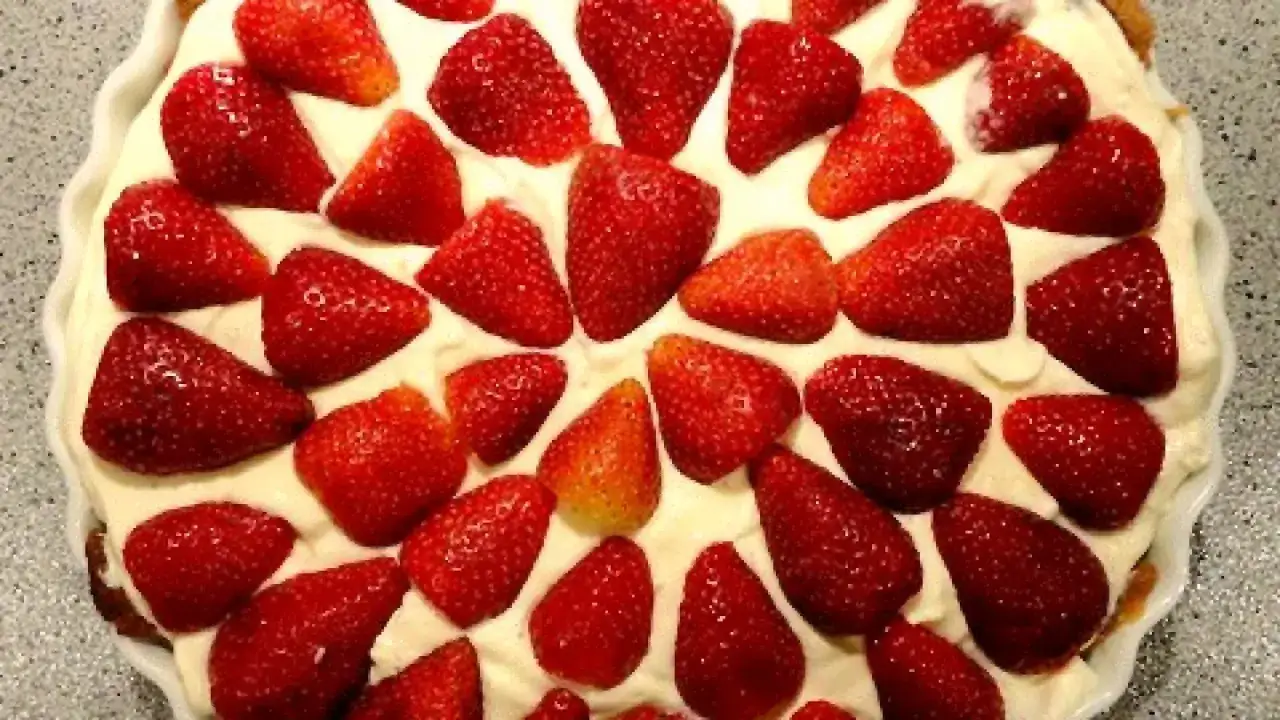 Bizcocho de fresa cubierto con crema y fresas frescas. Un postre delicioso y refrescante.
