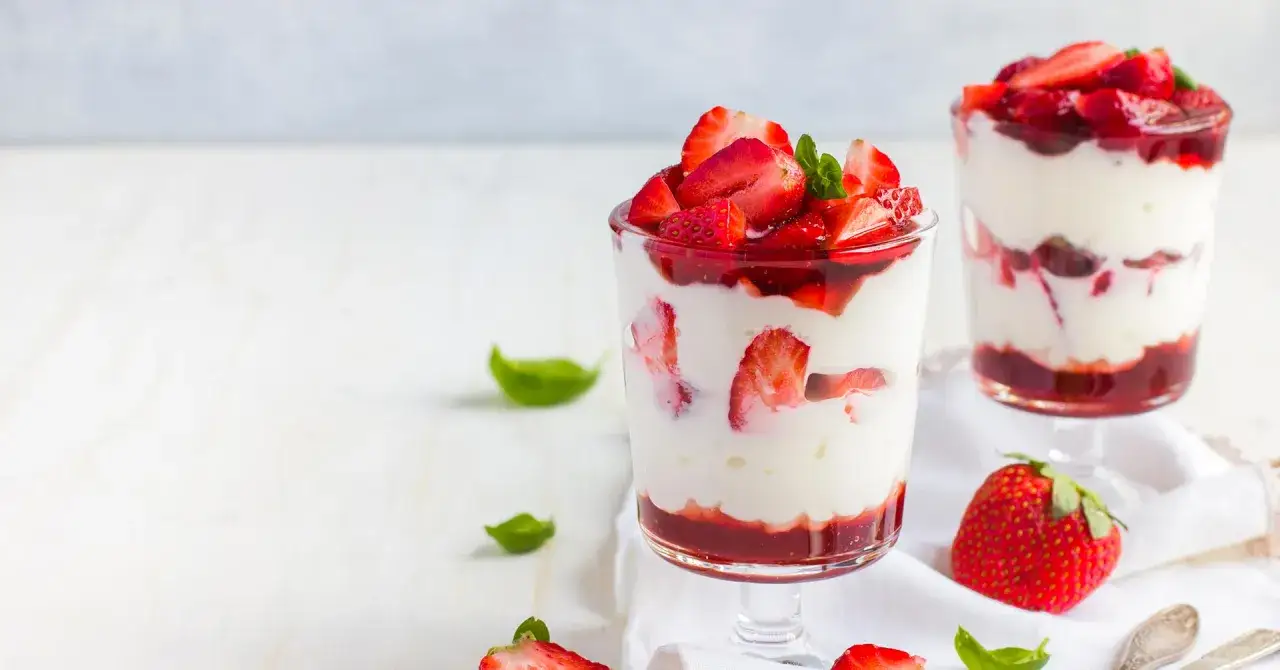 Deliciosos postres en copas con capas de crema blanca y fresas frescas, coronados con m&aacute;s fresas. Un placer visual y gustativo de fresas con leche condensada.