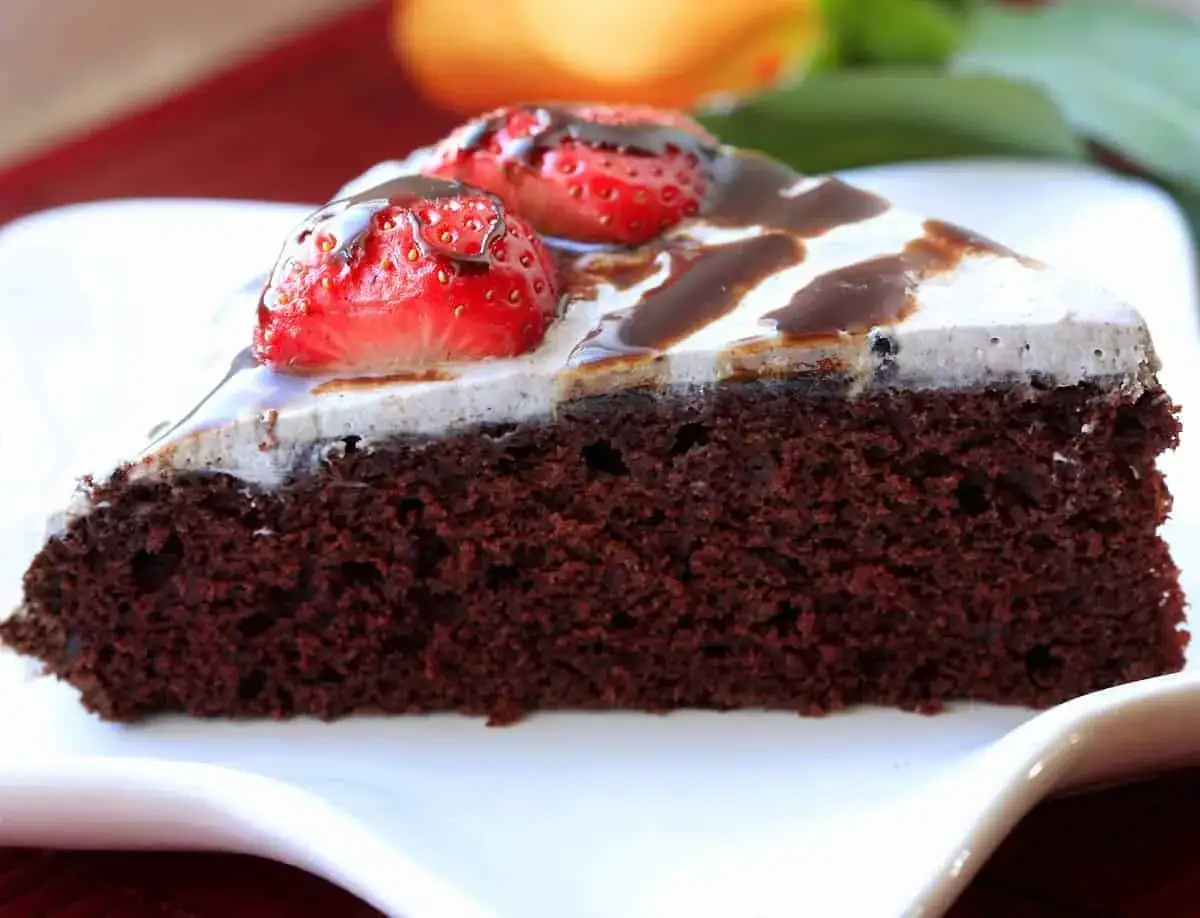 Deliciosa tarta vegana de chocolate, cubierta con crema y fresas frescas, ba&ntilde;ada en sirope de chocolate.