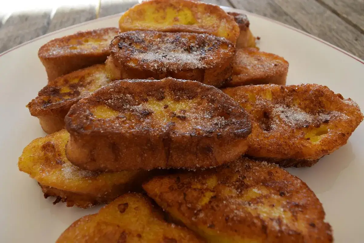 Torrijas doradas y crujientes, espolvoreadas con azúcar, perfectas para acompañar con leche condensada.