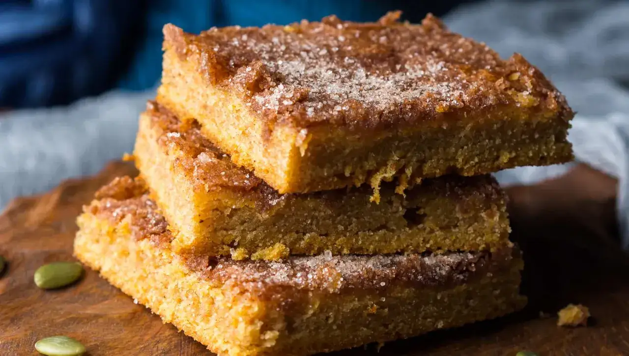 Delicioso brownie de calabaza, con una capa crujiente de az&uacute;car y canela, apilado sobre una tabla de madera.
