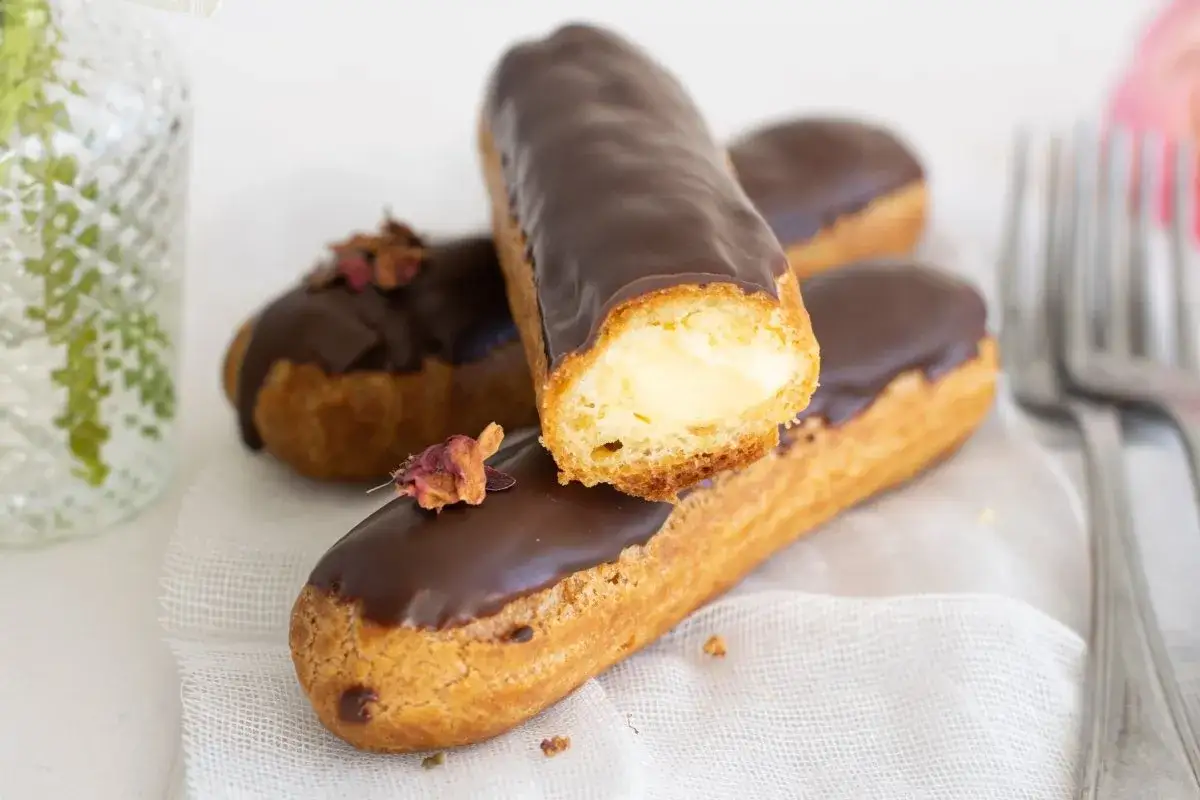 Deliciosos pastel eclair cubiertos de chocolate, rellenos de crema. Un placer para la vista y el paladar.
