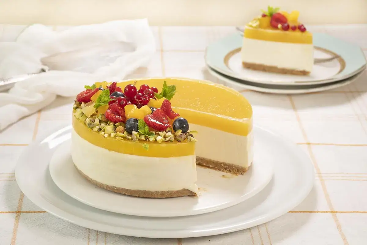 Tarta mango con frutos rojos y pistachos. Una porción ya cortada, lista para disfrutar.