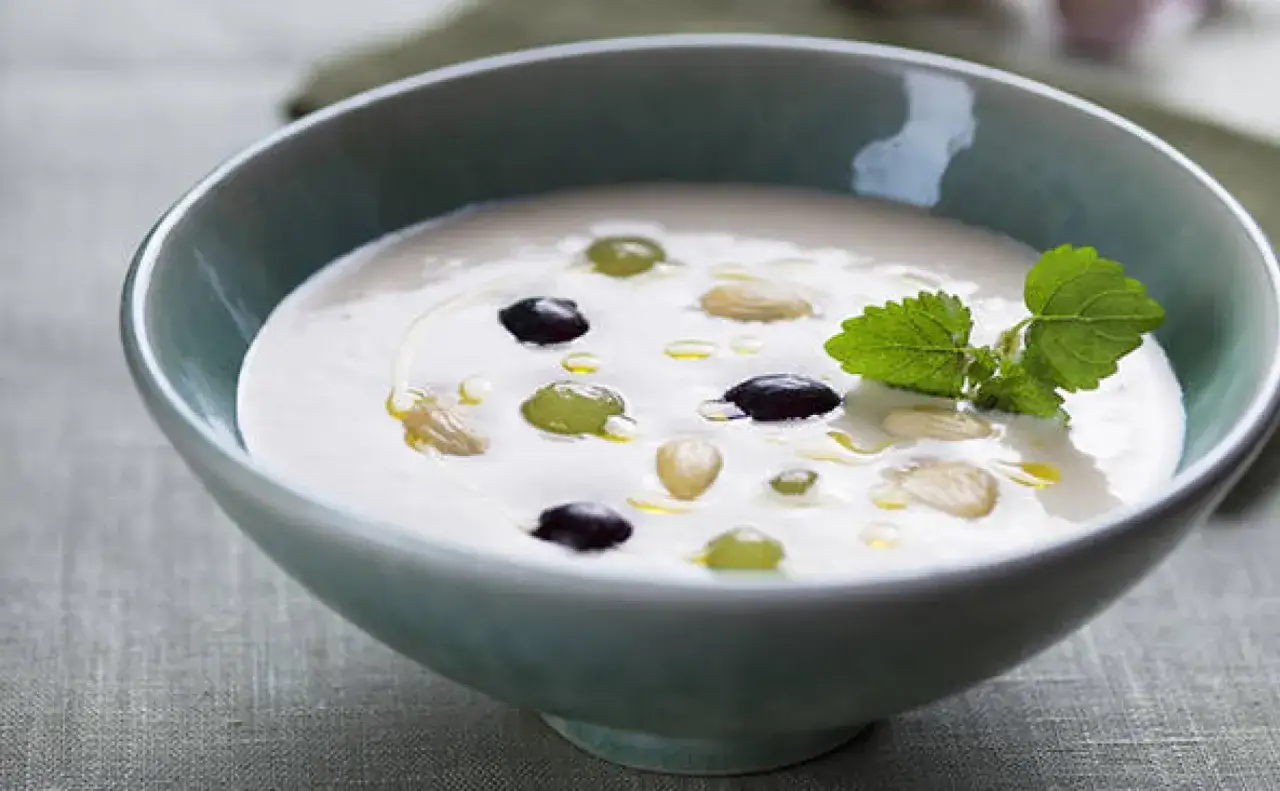 Deliciosa mazamorra cordobesa cremosa, adornada con uvas, almendras y un toque de menta fresca.