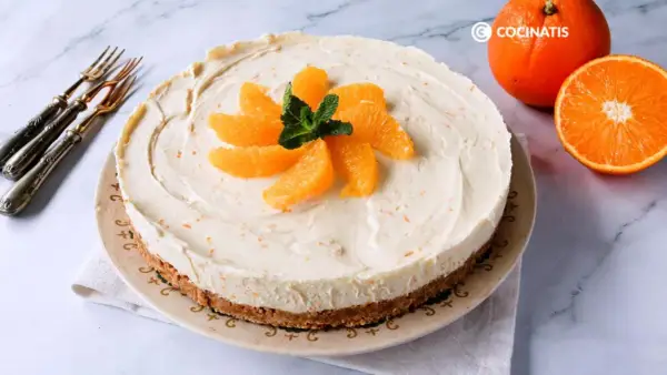 Tarta de naranja cremosa, decorada con gajos de naranja y menta. Perfecta para disfrutar de un postre refrescante.