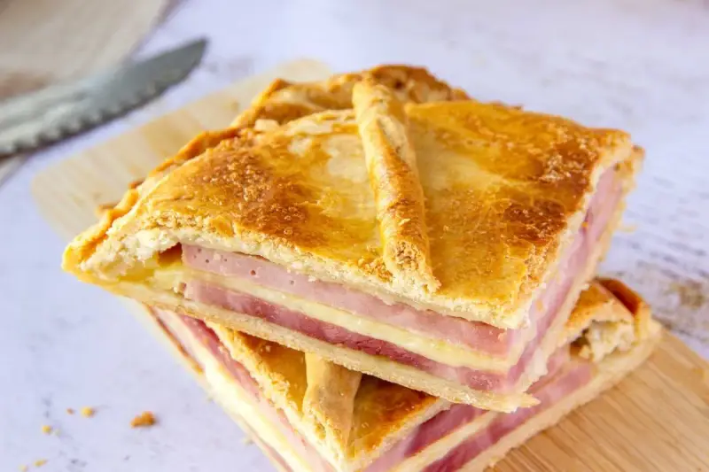 Dos porciones de empanadillas de jamón y queso, con capas doradas de masa y relleno generoso, listas para disfrutar.