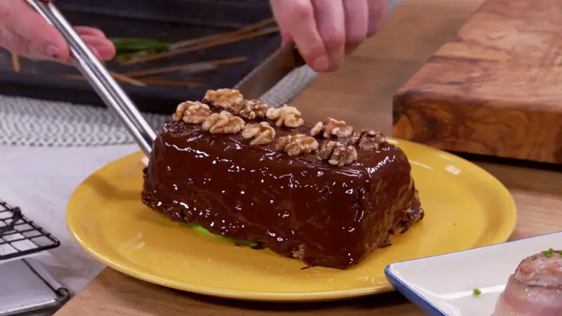 Un delicioso bizcocho de plátano cubierto de chocolate brillante y nueces, listo para ser cortado.