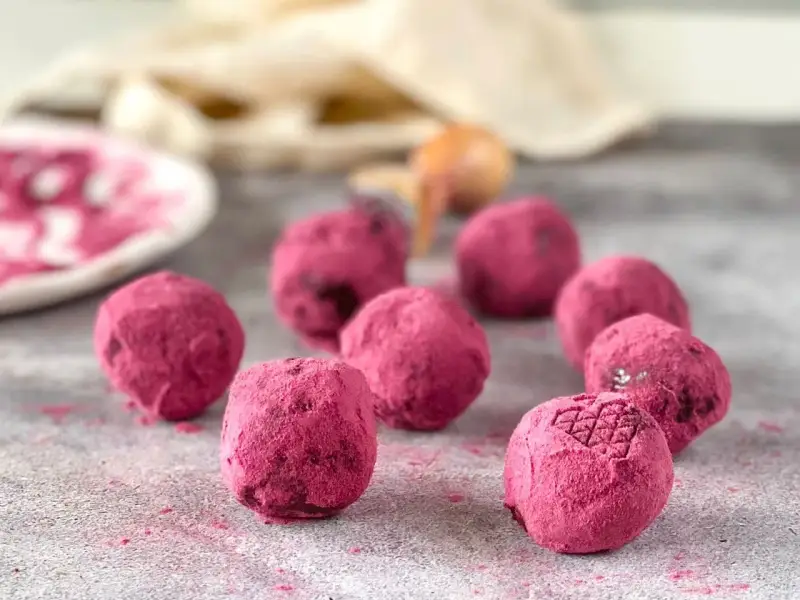 Deliciosas trufas de chocolate cubiertas de polvo rosa vibrante, algunas con un patrón grabado.