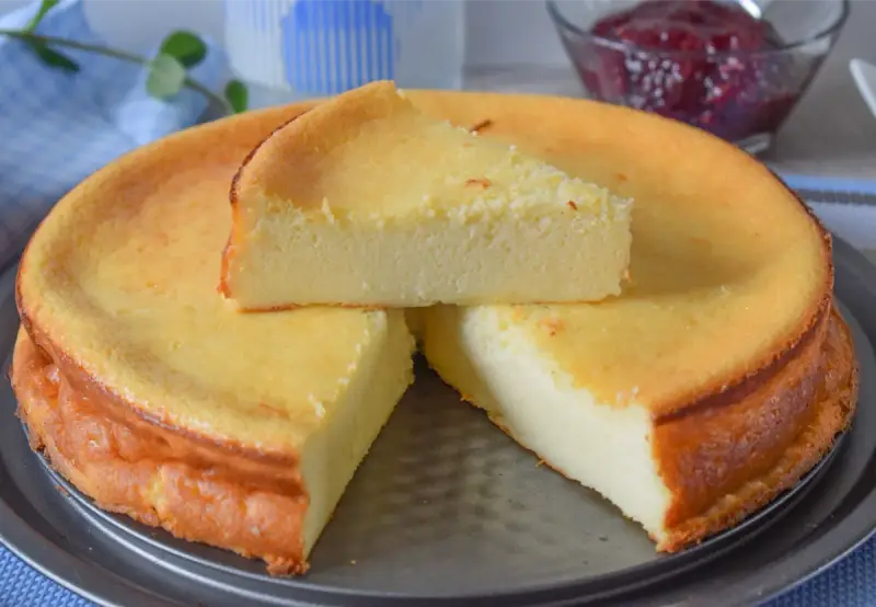 Tarta de queso y limón al horno, dorada y esponjosa, con una porción servida.